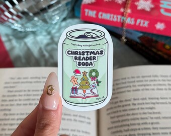 May include: A sticker in the shape of a soda can with the text "CHRISTMAS READER SODA". The can is light green with Christmas-themed illustrations, including a gingerbread man, a Christmas tree, and a wreath. The can is 200 ml.