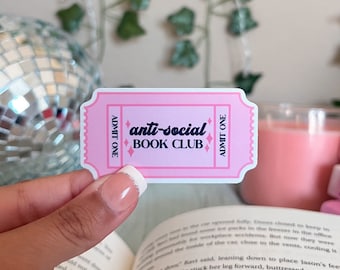 May include: Pink and white ticket sticker with the text "anti-social BOOK CLUB" in black lettering. The sticker has a dotted border and a diamond pattern.