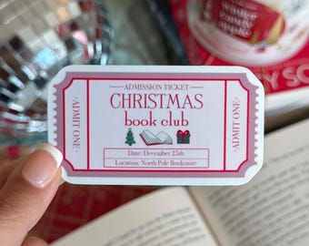 May include: A pink and white admission ticket for a Christmas book club. The ticket reads "ADMIT ONE" on both sides and says "CHRISTMAS book club" in the center. The date is December 25th and the location is North Pole Bookstore.