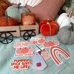 May include: A collection of fall-themed stickers with various designs, including pumpkins, a ghost, a rainbow, and text that says "fuzzy socks pumpkin spice sweater weather cozy fall vibes apple cider sweater weather pumpkin spice gives me life I'm a fall kind of girl pumpkin spice & everything nice".