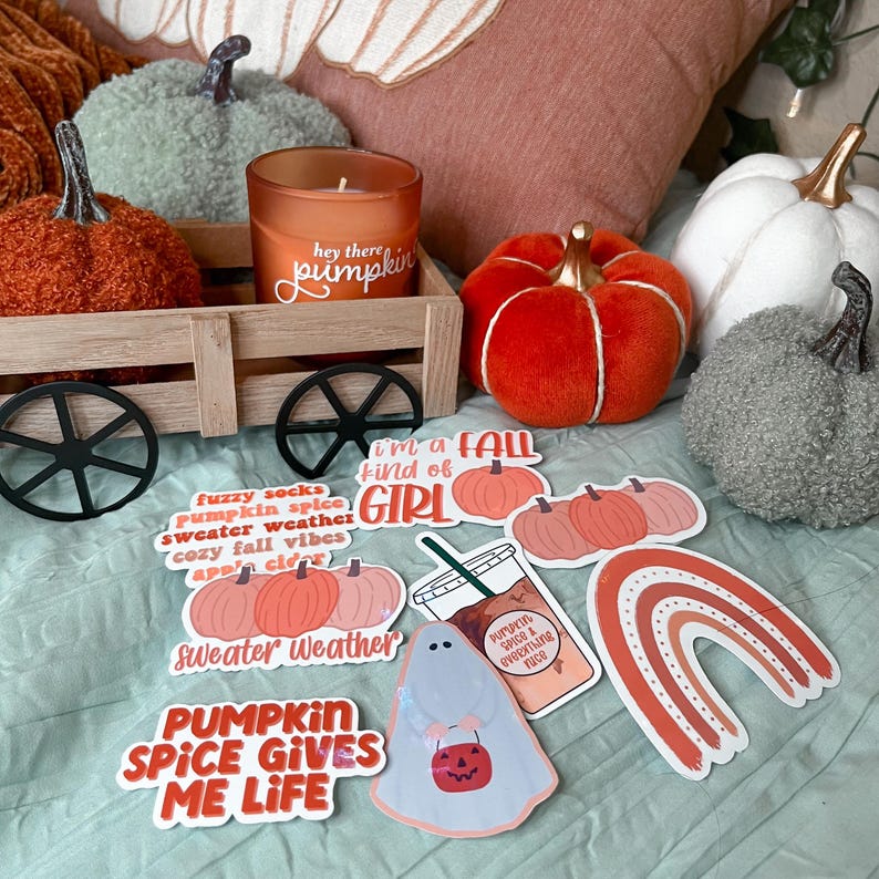 May include: A collection of fall-themed stickers with various designs, including pumpkins, a ghost, a rainbow, and text that says "fuzzy socks pumpkin spice sweater weather cozy fall vibes apple cider sweater weather pumpkin spice gives me life I'm a fall kind of girl pumpkin spice & everything nice".