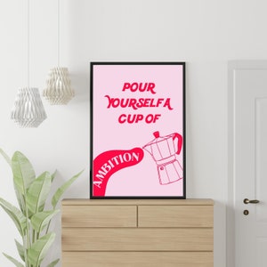 May include: A pink and black poster with the text "Pour yourself a cup of ambition" in pink. A red outline of a coffee pot pours the word "ambition" into a cup.