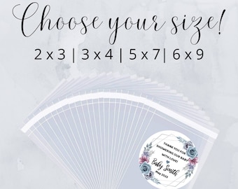 May include: A stack of clear plastic bags with a round sticker on top. The sticker has a watercolor floral design in shades of blue and pink with a gold geometric frame. The text on the sticker reads "Thank you for showering our baby with love! Baby Smith May 2023". The image also includes the text "Choose your size! 2x3|3x4|5x7|6x9" and "Completely Customizable".