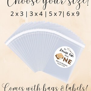 May include: A set of clear plastic bags with labels for a s'mores themed birthday party. The labels feature a brown and white illustration of a s'more with the text "It's S'more Fun Being One". The text "Milo's 1st Birthday August 6, 2025" is also included on the label. The image shows a variety of bag sizes: 2x3, 3x4, 5x7, and 6x9.