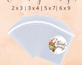 May include: A stack of clear plastic bags with a round sticker that says "Happy Thanksgiving" with a watercolor design of pumpkins and fall foliage. The text "Choose your size! 2x3|3x4|5x7|6x9" is at the top of the image and the text "Comes with bags & labels!" is at the bottom of the image.