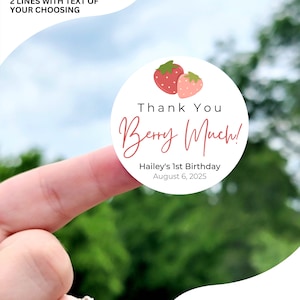 Może przedstawiać: Okrągła naklejka z białym tłem i czerwonymi truskawkami. Tekst "Thank You Berry Much!" jest napisany r&oacute;żowym kursywą. Tekst "Hailey's 1st Birthday August 6, 2025" jest napisany czarnym kolorem pod truskawkami. Naklejka jest dostępna w rozmiarach 1 cal, 1,5 cala, 1,75 cala, 2 cale, 2,25 cala i 3,33 cala. Naklejka na zdjęciu ma 2 cale.