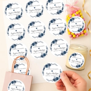 May include: Custom memorial stickers with a floral wreath design in navy blue. The stickers feature the text "Always in Our Hearts" and the name "Taylor Phillips" with dates. Available in various sizes from 1" to 3.33".