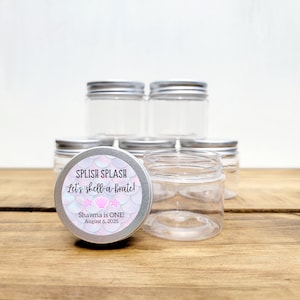 May include: A set of clear glass jars with silver lids. The jars are decorated with a sticker that says "Splish Splash Let's Shell-a-brate! Shawna is ONE! August 6, 2025".