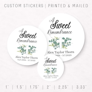 May include: White round stickers with the text "A Sweet Remembrance" in elegant script. Each sticker features a white cross surrounded by green foliage. The name "Alex Taylor Thorn" and dates are also included. Sizes range from 1" to 3.33".
