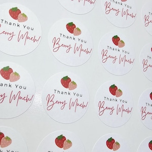 Może przedstawiać: Arkusz okrągłych naklejek z grafiką truskawki i tekstem "Thank You Berry Much!" nadrukowanym na r&oacute;żowo na każdej naklejce.