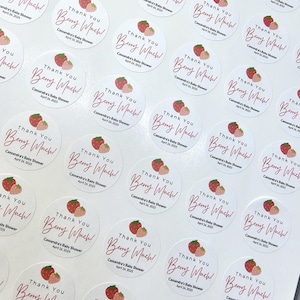 Może przedstawiać: Arkusz okrągłych, białych naklejek z grafiką r&oacute;żowej i czerwonej truskawki oraz tekstem "Thank You Berry Much!" Cassandra's Baby Shower April 26, 2025.