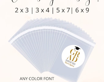 May include: A stack of clear plastic bags with gold graduation labels. The labels have the text "GRAD" with a graduation cap, "CLASS OF 2023", and a name. The text "Choose your size! 2x3 | 3x4 | 5x7 | 6x9" is at the top of the image. The text "ANY COLOR FONT" and "Comes with bags & labels!" is at the bottom of the image.