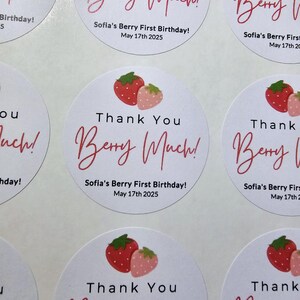 Może przedstawiać: Okrągłe białe naklejki z czerwonymi i r&oacute;żowymi truskawkami i tekstem "Thank You Berry Much!"  Sofia's Berry First Birthday! May 17th 2025