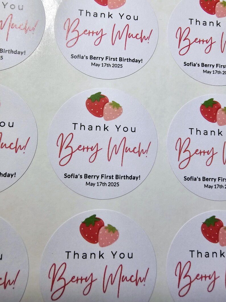 Może przedstawiać: Okrągłe białe naklejki z czerwonymi i r&oacute;żowymi truskawkami i tekstem "Thank You Berry Much!"  Sofia's Berry First Birthday! May 17th 2025