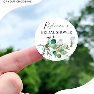 May include: Round stickers with a watercolor design of green leaves and white flowers. The text "Rebecca's Bridal Shower" is printed in black on the sticker. The stickers are available in various sizes: 1 inch, 1.5 inches, 1.75 inches, 2 inches, 2.25 inches, and 3.33 inches.
