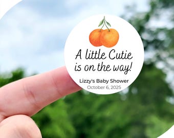 May include: A white circle sticker with a watercolor illustration of two orange mandarins with green leaves. The text reads "A little Cutie is on the way!" with "Lizzy's Baby Shower" and "October 6, 2025" below. The sticker is available in sizes 1 inch, 1.5 inches, 1.75 inches, 2 inches, 2.25 inches, and 3.33 inches. The sticker pictured is 2 inches.