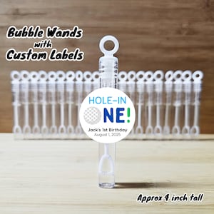 May include: Clear plastic bubble wands with white bubble wands. Each wand is approximately 4 inches tall. The wands have a custom label that reads "HOLE-IN-ONE!" with a golf ball graphic and "Jack's 1st Birthday August 1, 2025."