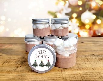 May include: A set of six silver jars filled with hot chocolate mix and marshmallows. The jars are stacked in a pyramid shape and have a label that says "Merry Christmas" with three Christmas trees on it.