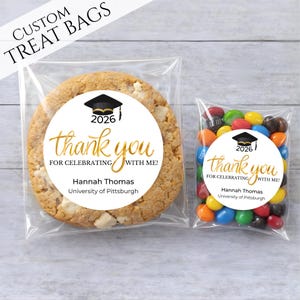 May include: Two clear treat bags, one with a large cookie and the other with colorful candies. Both bags have a circular sticker with a graduation cap, the year 2026, and the words "thank you" in gold script. The text "FOR CELEBRATING WITH ME!" and a name and university are also included.