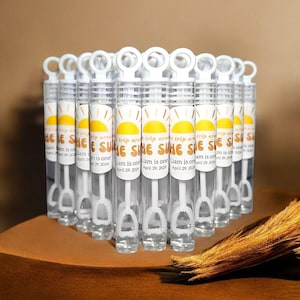 May include: A set of clear plastic bubble wands with white handles and labels that say "The Sun Trip Around Liam is One April 29, 2024".