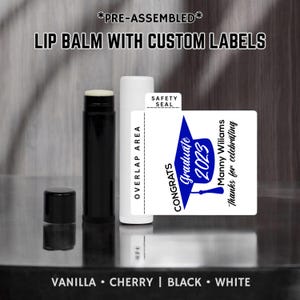 May include: A white lip balm tube with a blue and white graduation cap label. The label says "Congrats Graduate 2023" and "Manny Williams Thanks for celebrating".