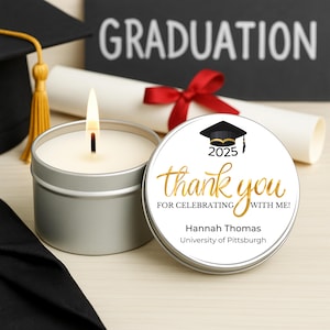 May include: A white candle with a gold lid and a black and gold graduation cap sticker. The sticker says "2025 thank you for celebrating with me! Hannah Thomas University of Pittsburgh".