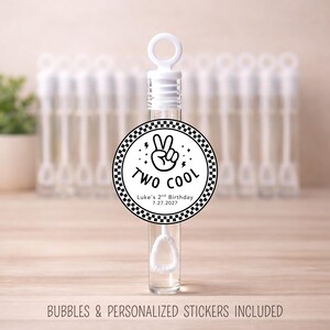 May include: Clear bubble wand with a white top and a round sticker that says "TWO COOL" with a peace sign. The sticker also includes "Luke's 2nd Birthday 7.27.2027". Bubbles and personalized stickers included.