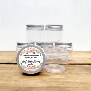 May include: Set of clear glass jars with silver lids, decorated with floral labels. The labels say "Thank you for showering our baby with love! Lacy's Baby Shower 5.24.2023".