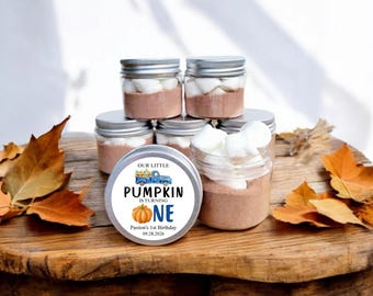 May include: A set of six small glass jars with silver lids filled with hot chocolate mix and marshmallows. The jars are decorated with a round sticker that says "Our Little Pumpkin is Turning One" with a blue truck and a pumpkin. The sticker also includes the name "Paxton's 1st Birthday" and the date "09.28.2026".