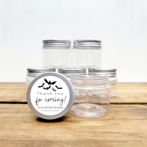 May include: Clear glass jars with silver lids, some with labels that say "Thank You for coming! Tara's Bridal Shower October 6, 2025" and feature a black bat design.