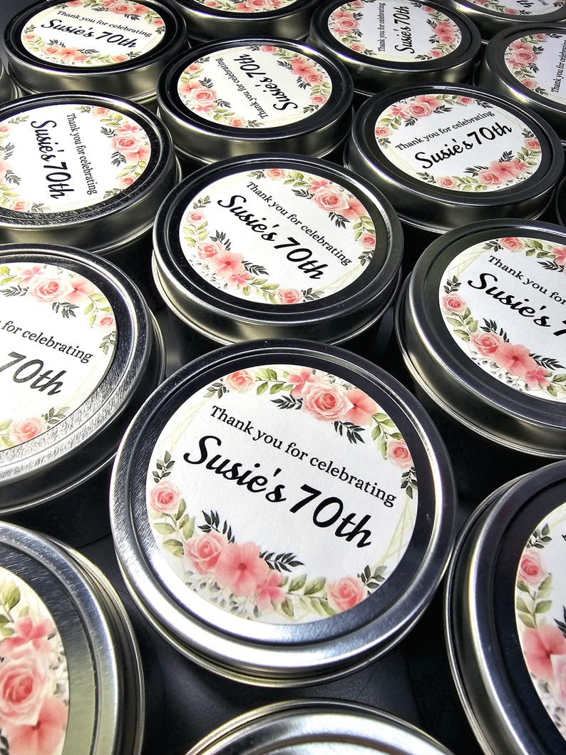 May include: A collection of small silver tins with floral designs and the text "Thank you for celebrating Susie's 70th" printed on the lids.