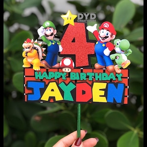 May include: A red, green, and blue cake topper with the characters Mario, Luigi, Bowser, Yoshi, and a star. The topper says "Happy Birthday Jayden" and has a red number 4 in the center.