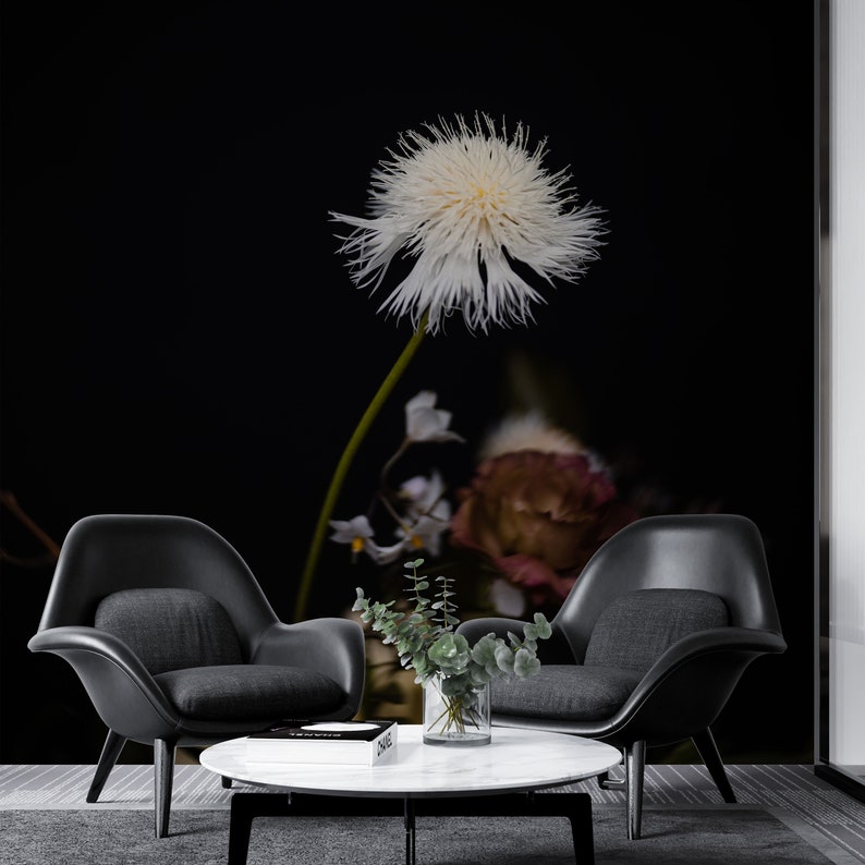 May include: A white dandelion-like flower with a long stem, against a black background. Two black chairs and a white marble coffee table are in the foreground.