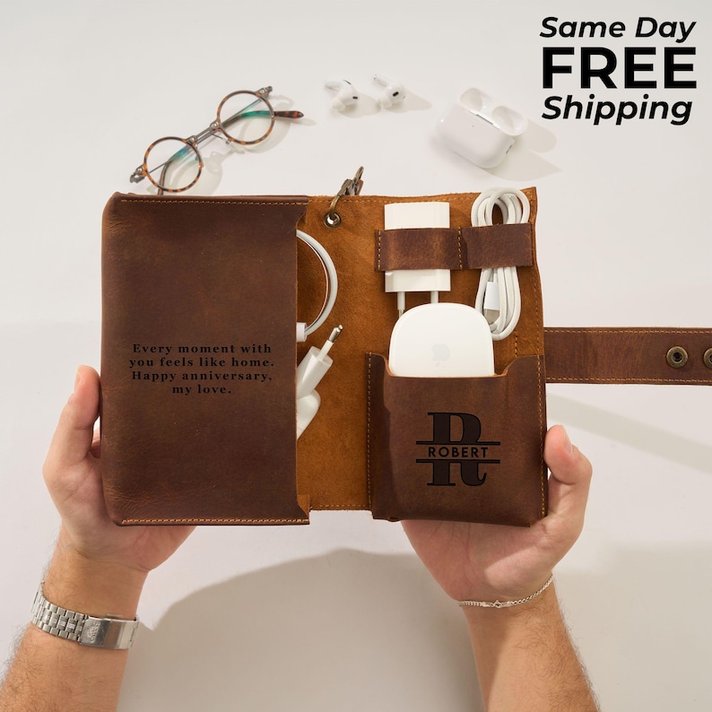 May include: A brown leather tech organizer with a personalized pocket. The organizer holds a white mouse, charger, and cables. Text on the organizer reads, "Every moment with you feels like home. Happy anniversary, my love."