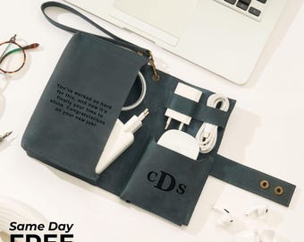 May include: A teal leather tech organizer with a handle, holding white chargers, a mouse, and cables. The organizer has the initials "cDs" and the text "You've worked so hard for this... Congratulations on your new job!" A laptop is in the background.