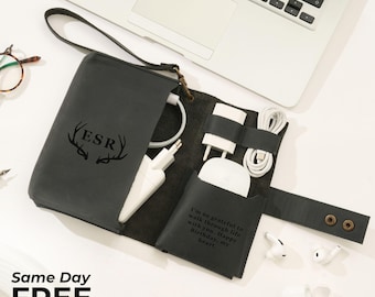 May include: A black leather tech organizer with a handle, holding white charging accessories. The organizer is open, revealing a pocket with a quote and a section for cables and chargers. The initials "ESR" are engraved on the front.