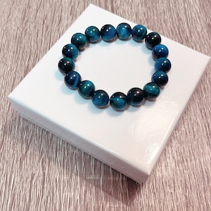 May include: A blue tiger's eye beaded bracelet on a white background.