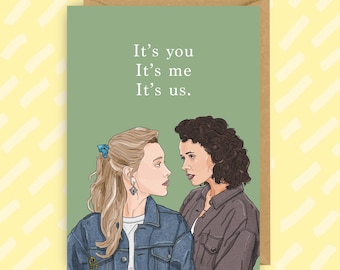 May include: A green card with the text "It's you It's me It's us."  Two women are illustrated looking at each other. The woman on the left has blonde hair and is wearing a blue denim jacket. The woman on the right has brown hair and is wearing a brown jacket.