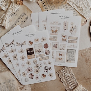 May include: Four sheets of stickers featuring illustrations of butterflies, flowers, and vintage-style text. The stickers are on a white background with a brown border. The text on the stickers reads "albanlovehandmade" and "stickers".