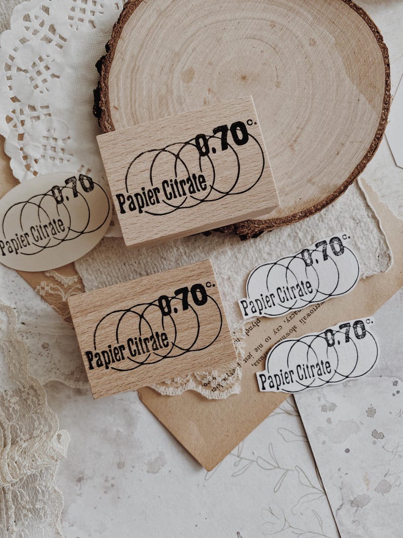 May include: Two rectangular wooden stamps and three paper cutouts featuring a black ink design of three overlapping circles, the text "Papier Citrate," and the number "0.70c." The stamps have a light wood grain finish and a rectangular shape.