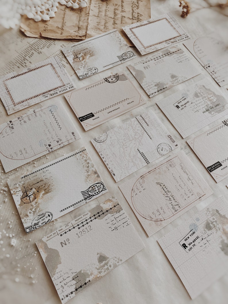 May include: A collection of vintage-style postcards with distressed edges and faded ink. The postcards feature various designs, including a map, a compass, and a stamp with the words "By Air Mail".