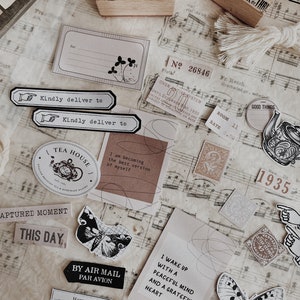 May include: A collection of vintage-style paper ephemera with a tea house theme. The ephemera includes stamps, stickers, and paper scraps with images of butterflies, teacups, and flowers. The text on the ephemera includes phrases like "Tea House", "By Air Mail", "I Wake Up With A Peaceful Mind", and "Captured Moment".