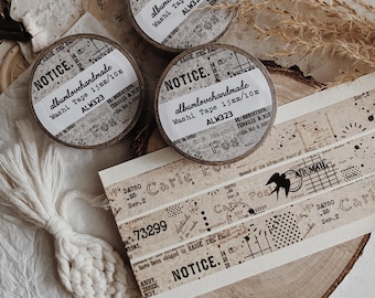 May include: Three rolls of beige washi tape with vintage postal-themed designs, including black text reading NOTICE, albumlovehandmade, Washi Tape 15mm/10m, ALW323, and Air Mail, alongside various stamps, grid patterns, and numbers on a paper strip.