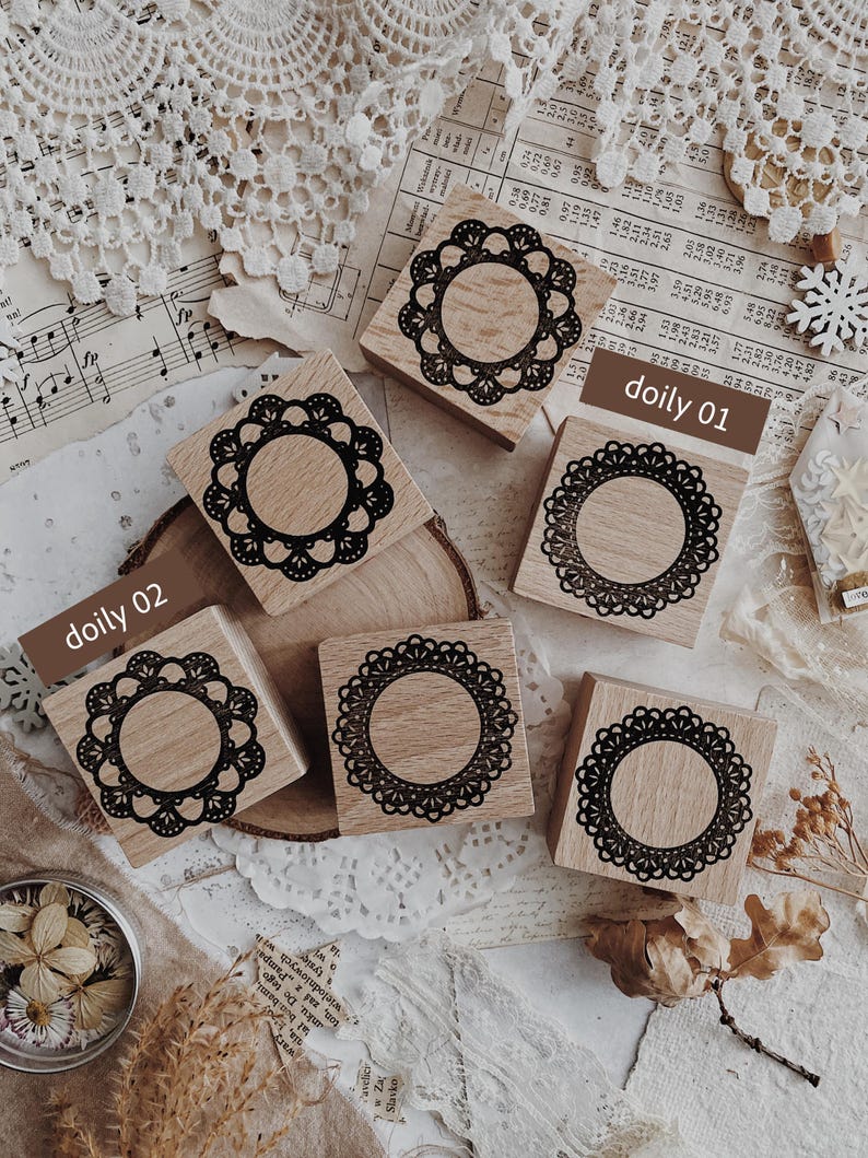 May include: Five square wooden stamps featuring intricate black circular lace doily patterns on the top surface. Two of the stamps are labeled with the text doily 01 and doily 02. The stamps have a light wood grain finish and a smooth texture.