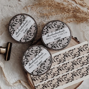 Puede incluir: Tres rollos de cinta washi con un patrón de hojas botánicas negras sobre un fondo beige claro. Cada etiqueta dice albumlovehandmade Washi Tape 15mm/10m ALW907. Se muestran tres tiras de la misma cinta con el diseño de hojas repetitivo.