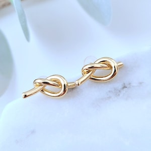 May include: A pair of gold knot-shaped earrings. The earrings are simple and elegant, and would make a great gift for any occasion.