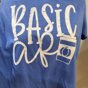 Peut inclure: T-shirt bleu avec l'inscription "BASIC AF" en lettres blanches usées. Le "AF" est relié à un dessin de tasse à café. Le t-shirt est fait d'une matière douce.