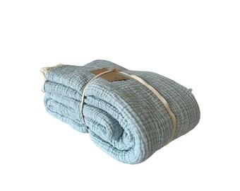 May include: A light blue waffle weave throw blanket folded and tied with a white ribbon. The blanket has a soft, textured surface.