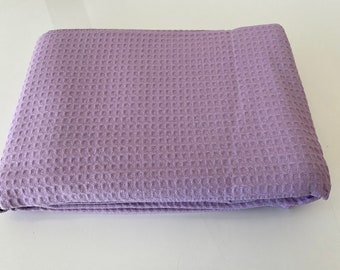 May include: A soft, lavender waffle weave throw blanket. The blanket is folded in half and is lying on a white surface.