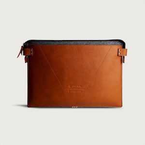 May include: A brown leather laptop sleeve with a grey felt lining and a zip closure. The sleeve has a stitched design and the text "OneStyle" is embossed on the front.